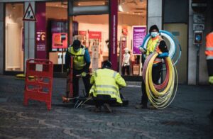 This image is of fiber cables being installed under city streets by cable workers. 